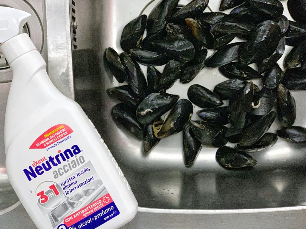 Spary per pulire l'acciaio poggiato sul lavabo pieno di cozze